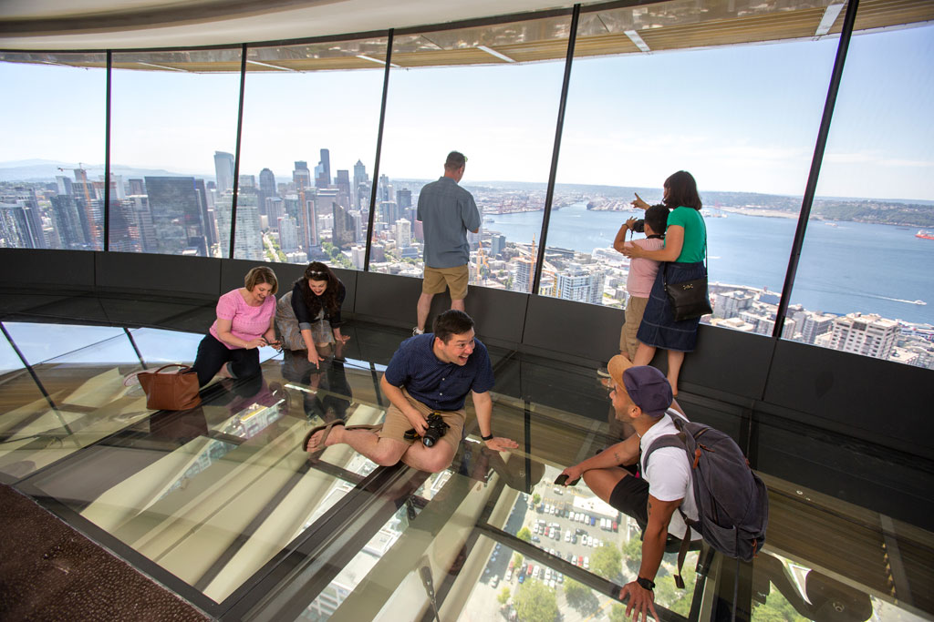 Guests sit on The Loupe - the Space Needle's newly-installed glass floor. Courtesy of John Lok and Space Needle LLC.