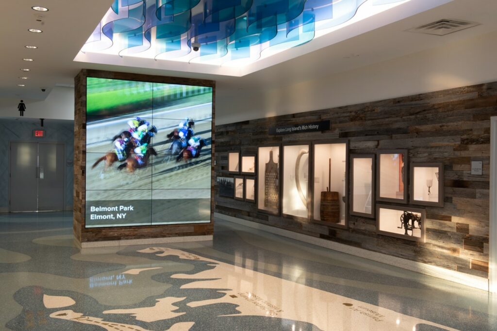 Common design features such as floor maps and artifact walls (shown here at the Long Island Welcome Center) create cohesive programming, while allowing the individuality of each region shine. Courtesy of Stantec