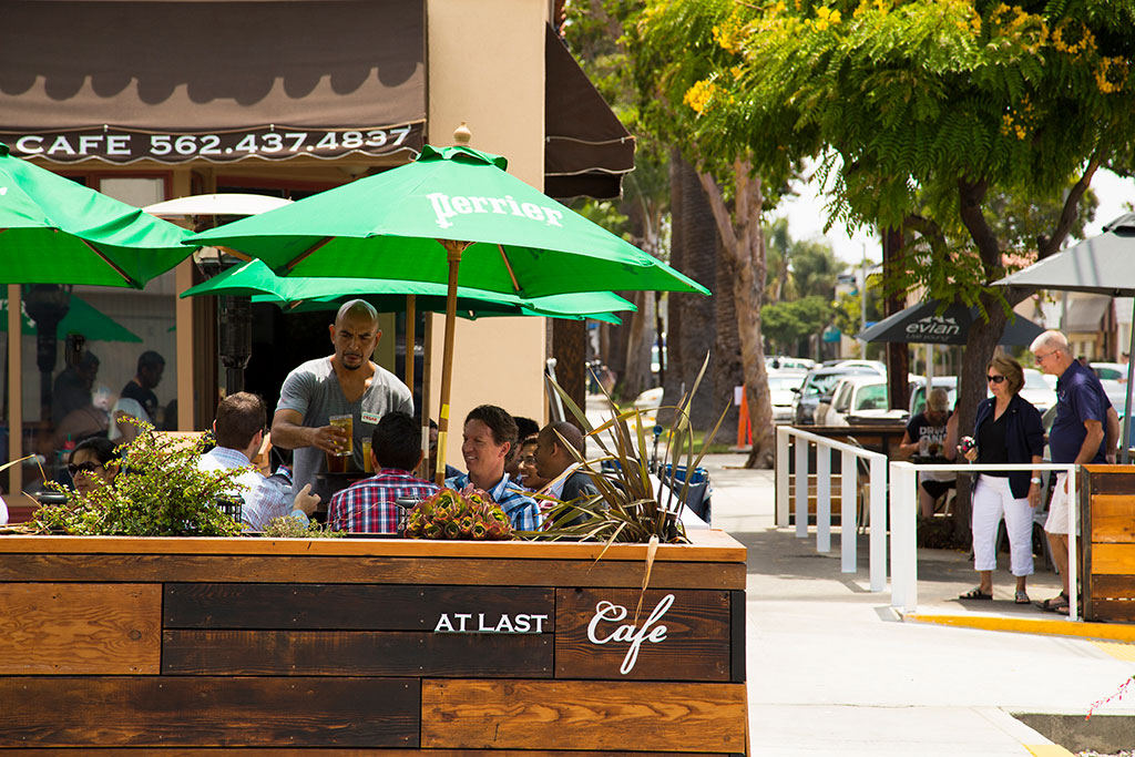 An existing parklet, At Last Café in Long Beach, offers sidewalk dining, pictured here pre-Covid-19. The At Last Cafe Parklet site plan illustrates how this project, built as a bulb-out, added a four-way stop that calms traffic and encourages pedestrian activity. 